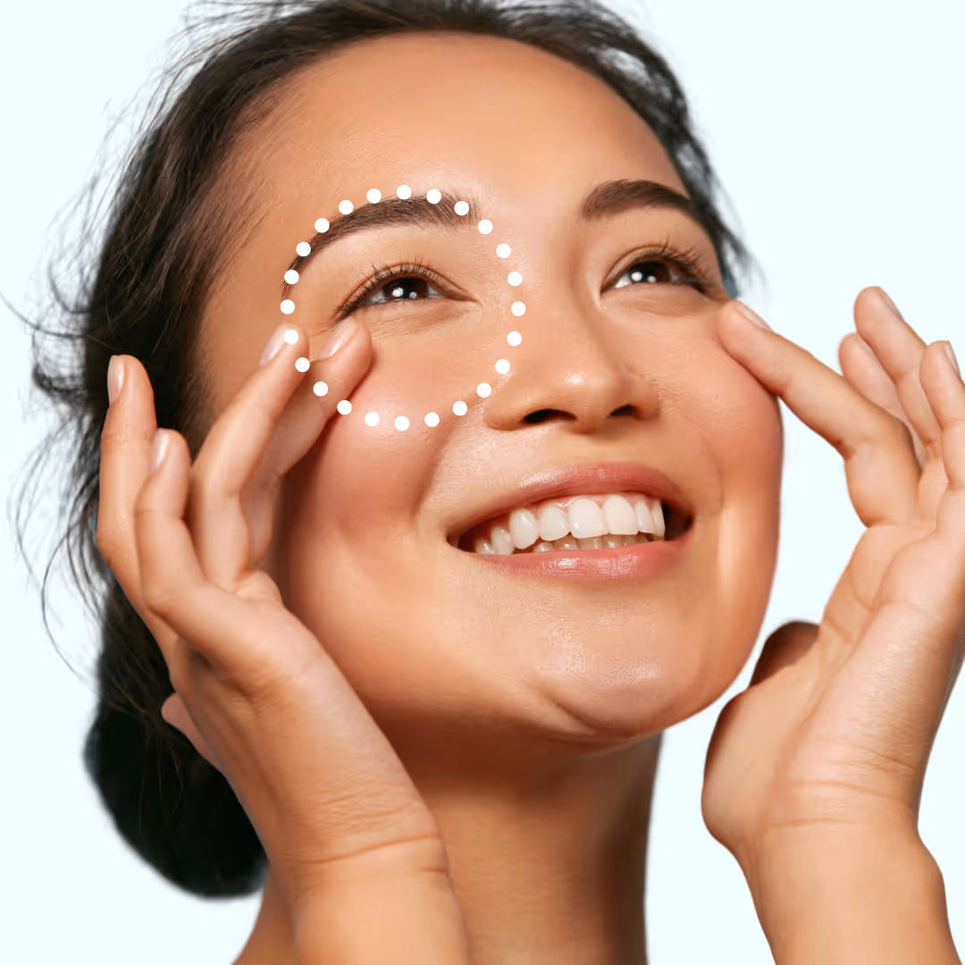 Smiling woman touching skin around her eyes with a circular dotted line highlighting the area under one eye.